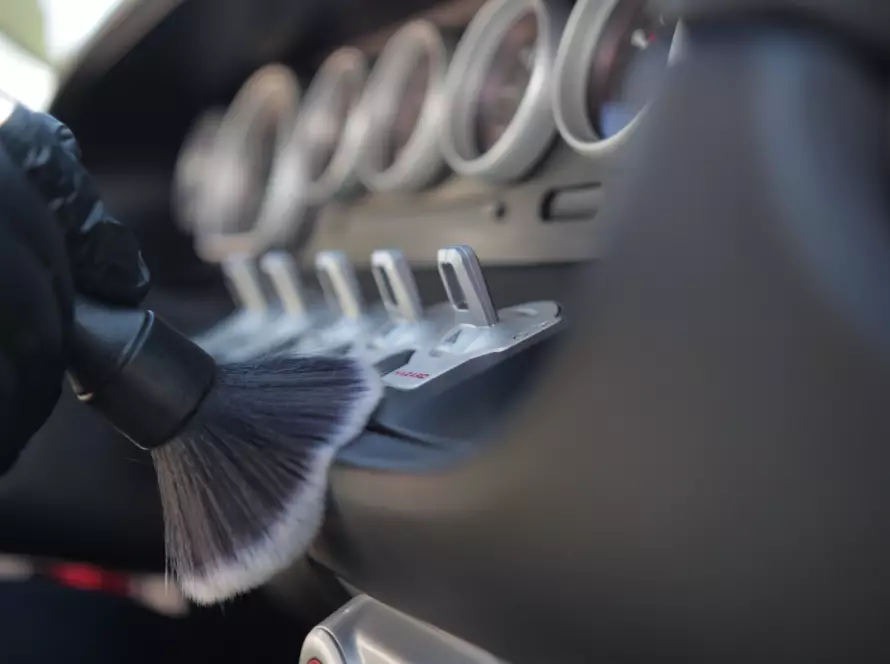 Interior car detailing with soft brush cleaning dashboard controls by Absolute Precision Custom Detailing for a spotless, professional finish.